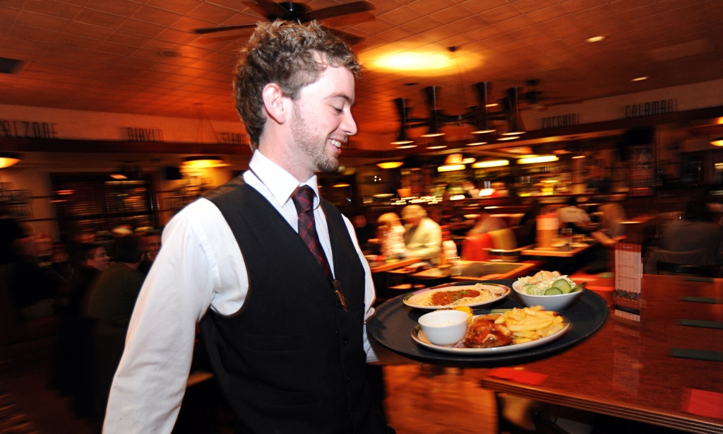 A waiter rushes with a tray of food in a busy restaurant Bradford West Yorkshire.