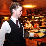 A waiter rushes with a tray of food in a busy restaurant Bradford West Yorkshire.